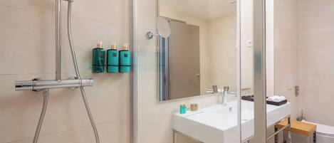 A modern bathroom with a glass shower enclosure, a white sink, and a mirror.