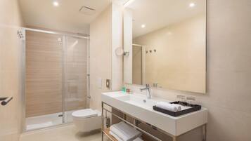 A modern bathroom with a glass shower enclosure, a white sink, and a large mirror.