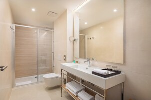 A modern bathroom with a glass shower enclosure, a white sink, and a large mirror.