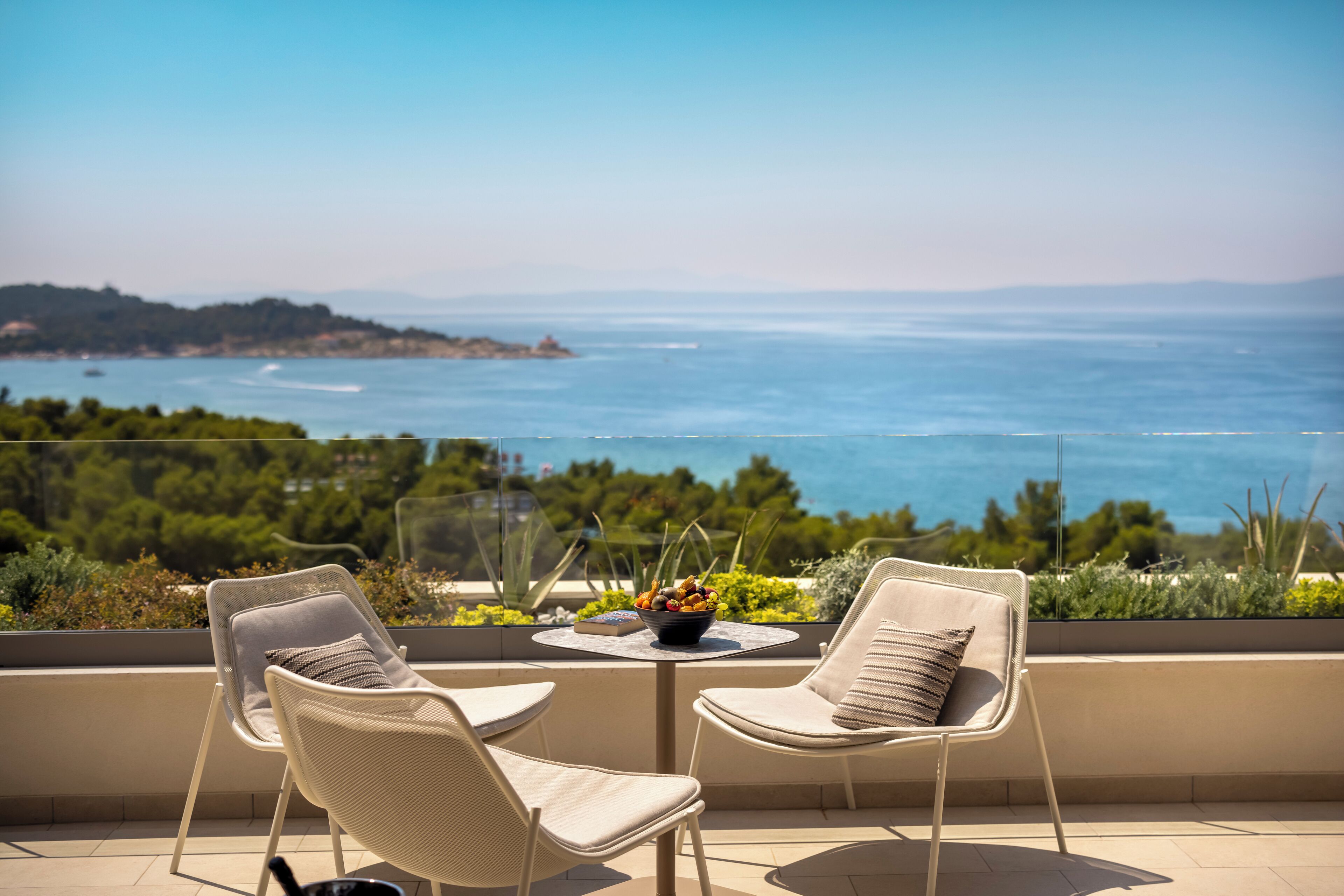 Ein Balkon mit zwei Stühlen und einem Tisch mit Blick auf die Küste.