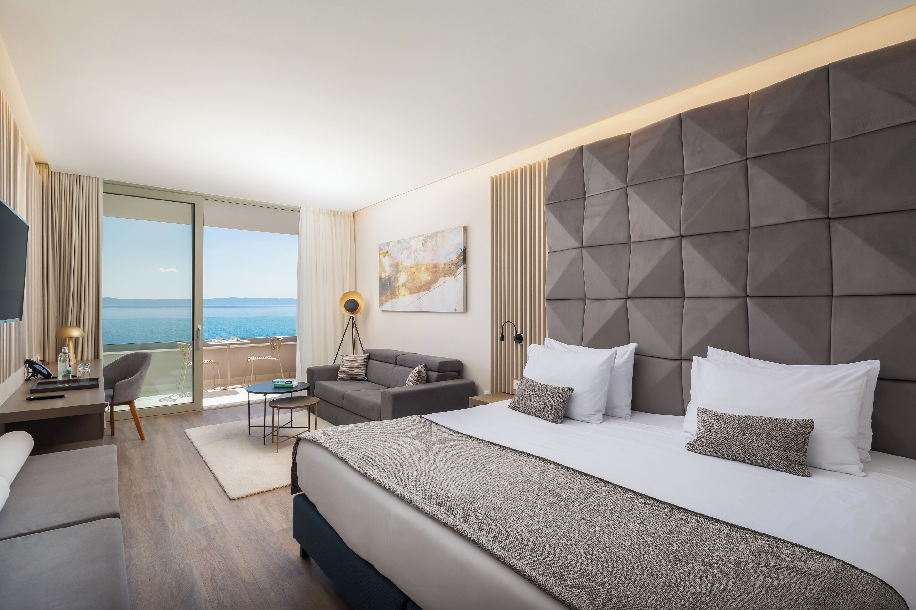 Una habitación de hotel moderna con una cama grande, un escritorio, una silla y vistas al mar.