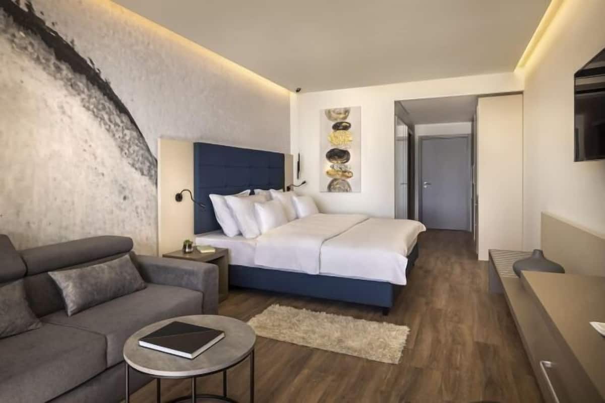 Een moderne slaapkamer met een bed, een bank, een klein tafeltje en een wanddecoratie.