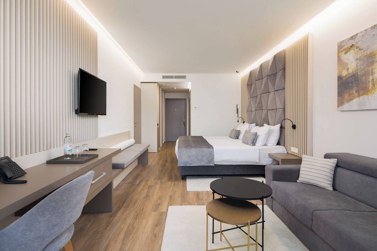 Een moderne hotelkamer met een bed, een bureau, een bank en een televisie.