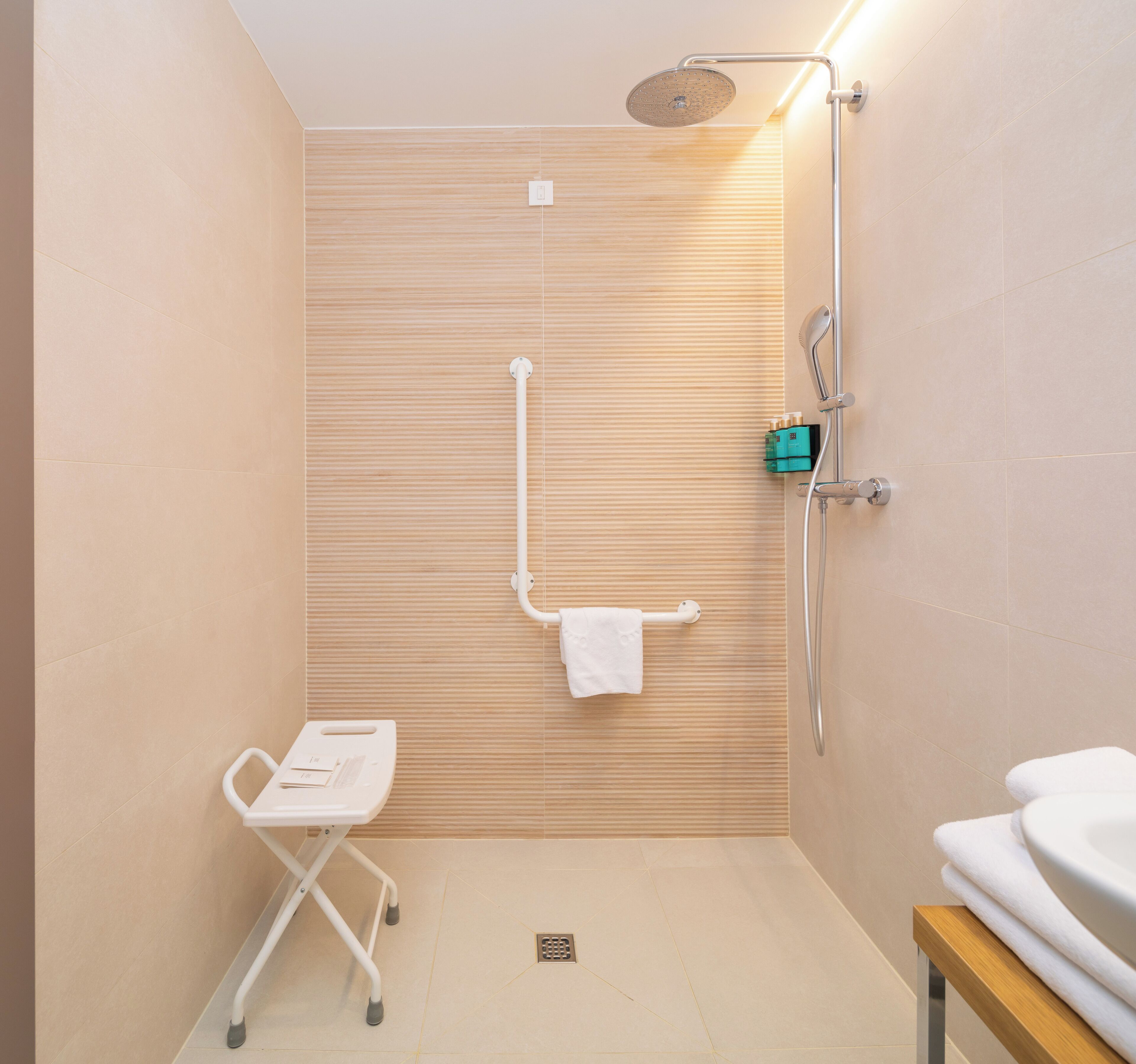 Un baño moderno con ducha, inodoro y un banco accesible para sillas de ruedas.