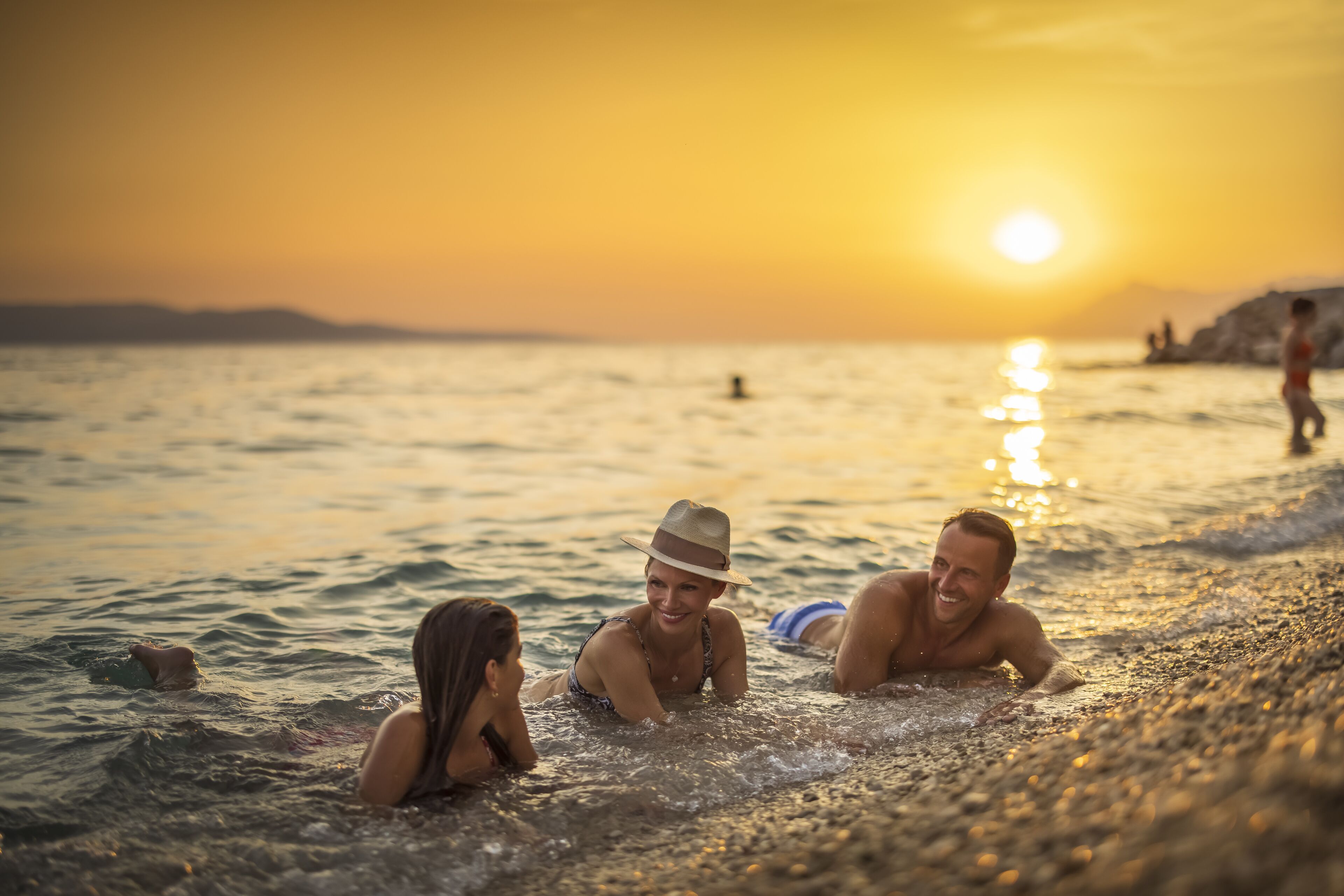 Een strandscène met mensen die in de zonsondergang zwemmen.