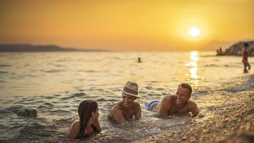 Een strandscène met mensen die in de zonsondergang zwemmen.
