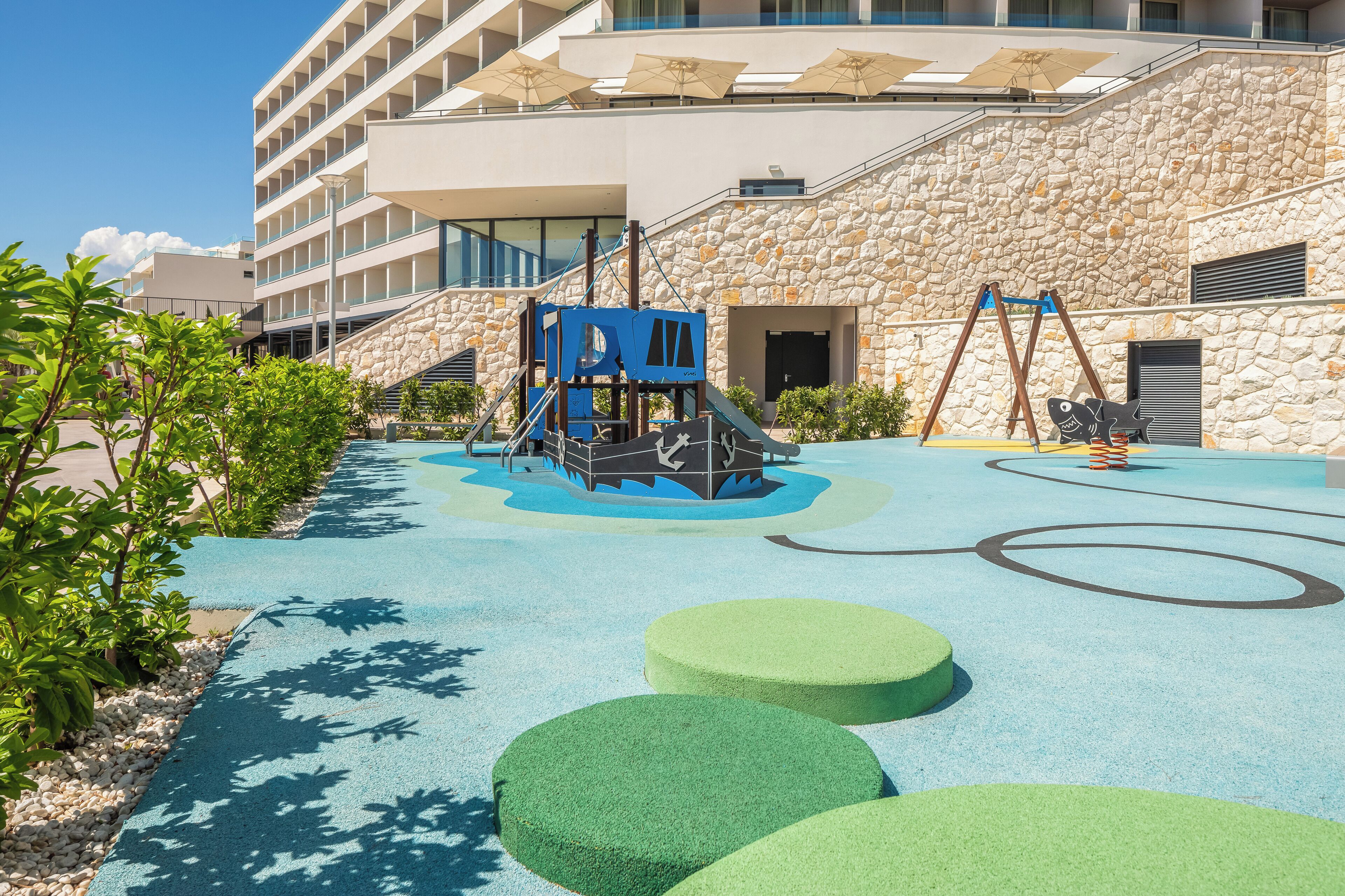 A children's play area with a climbing structure, swings, and a pool.