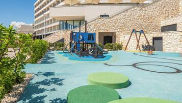A children's play area with a climbing structure, swings, and a pool.