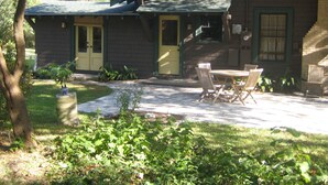 Ein Haus mit einer Veranda, einem Essbereich mit Gartenmöbeln und einem kleinen Garten.