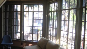 Ein Zimmer mit großem Fenster, einem Sessel und einer Couch.