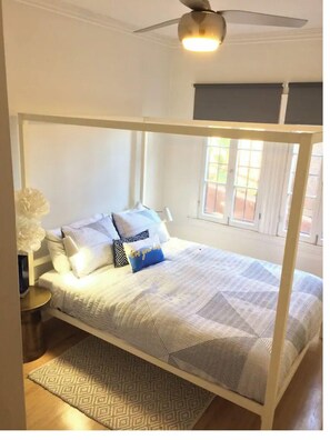 A bed with a white frame, patterned bedding, and a blue pillow with text.