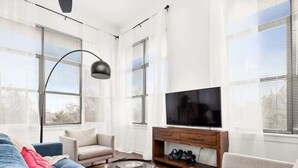 A modern living room with a sofa, chairs, a coffee table, a TV, and a plant.