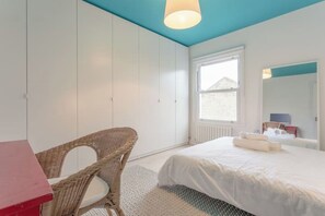 A bedroom with a bed, a chair, a window, and a mirror. - Stylish & vast 2 bedroom apt in authentic London (London)