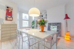 A modern kitchen with a white island, clear chairs, a vase with flowers, and a large pendant light. - Stylish & vast 2 bedroom apt in authentic London (London)