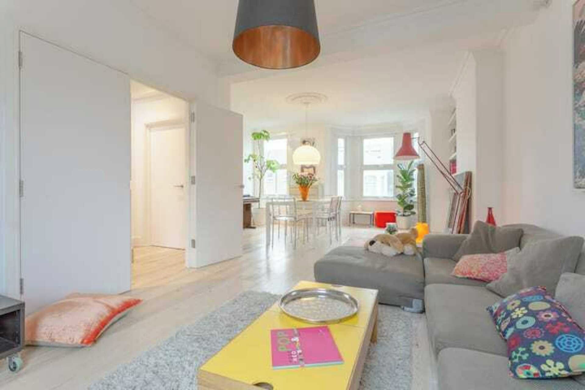 A spacious living area with a sofa, a coffee table, and a dining area in the background.