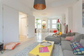 A spacious living area with a sofa, a coffee table, and a dining area in the background. - Stylish & vast 2 bedroom apt in authentic London (London)