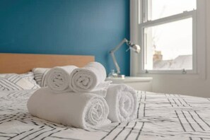 A neatly made bed with rolled white towels and a striped bedspread. - Stylish & vast 2 bedroom apt in authentic London (London)
