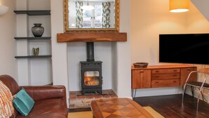 Una sala de estar acogedora con chimenea, un sofá, una mesa de centro y un televisor.