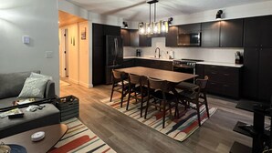 A modern kitchen with dark cabinets, a central island, and pendant lighting. - Jay Peak's Premier Ski-In / Ski-Out Location-just steps from the trail (Jay)