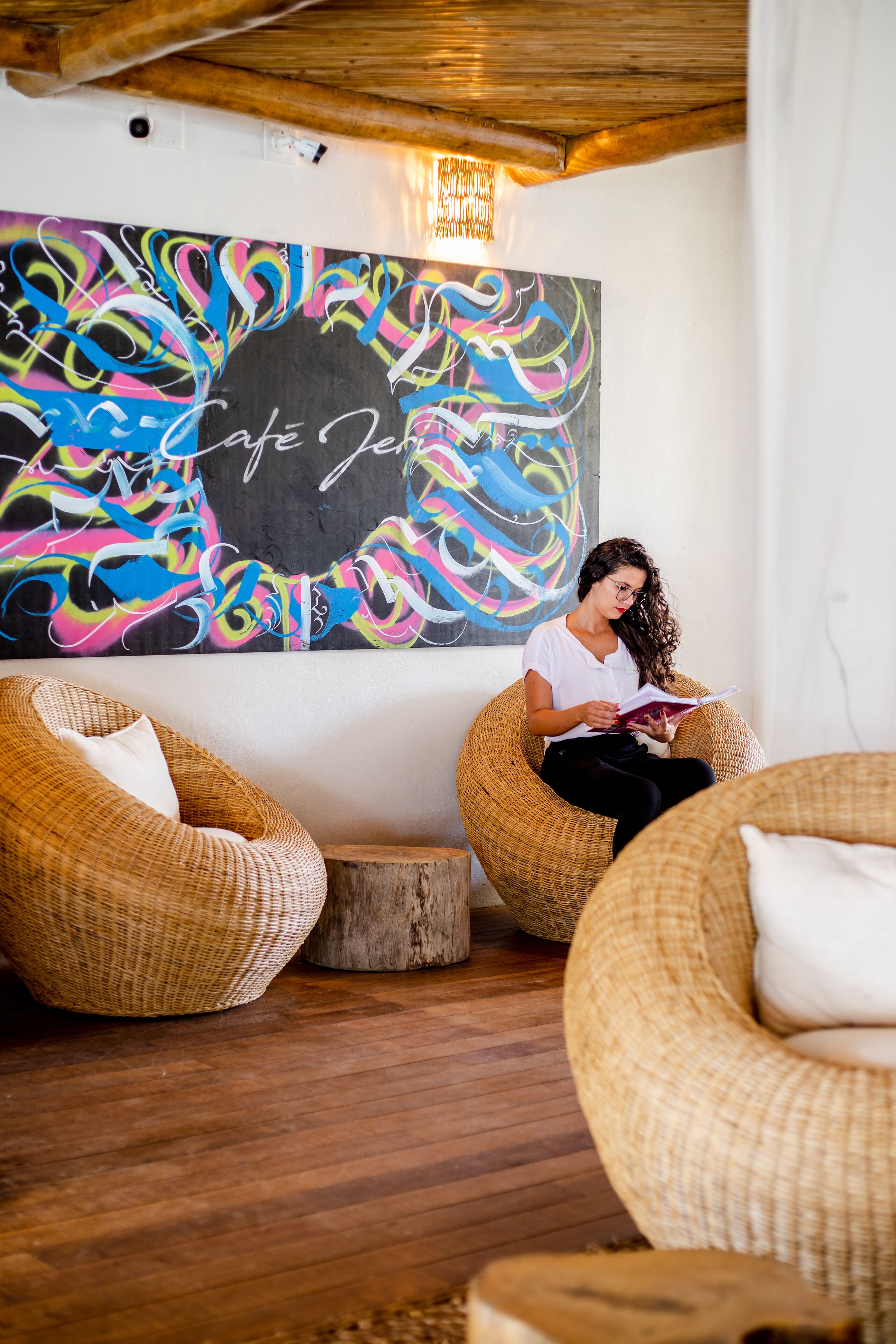 A room with wicker chairs, a wooden floor, and a colorful abstract painting on the wall.