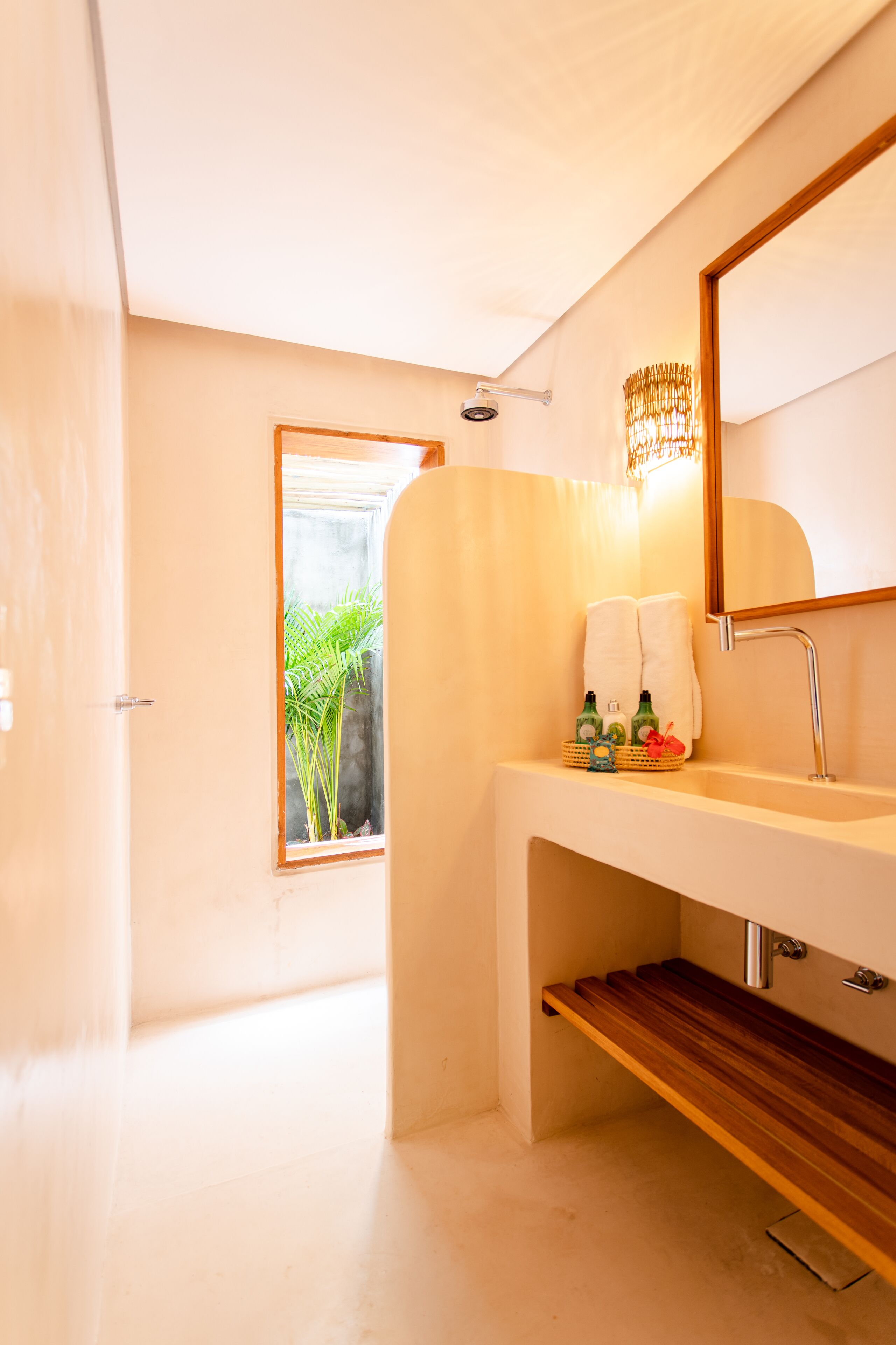 Casa de banho moderna com um espelho grande, chuveiro e lavatório com produtos de higiene pessoal.