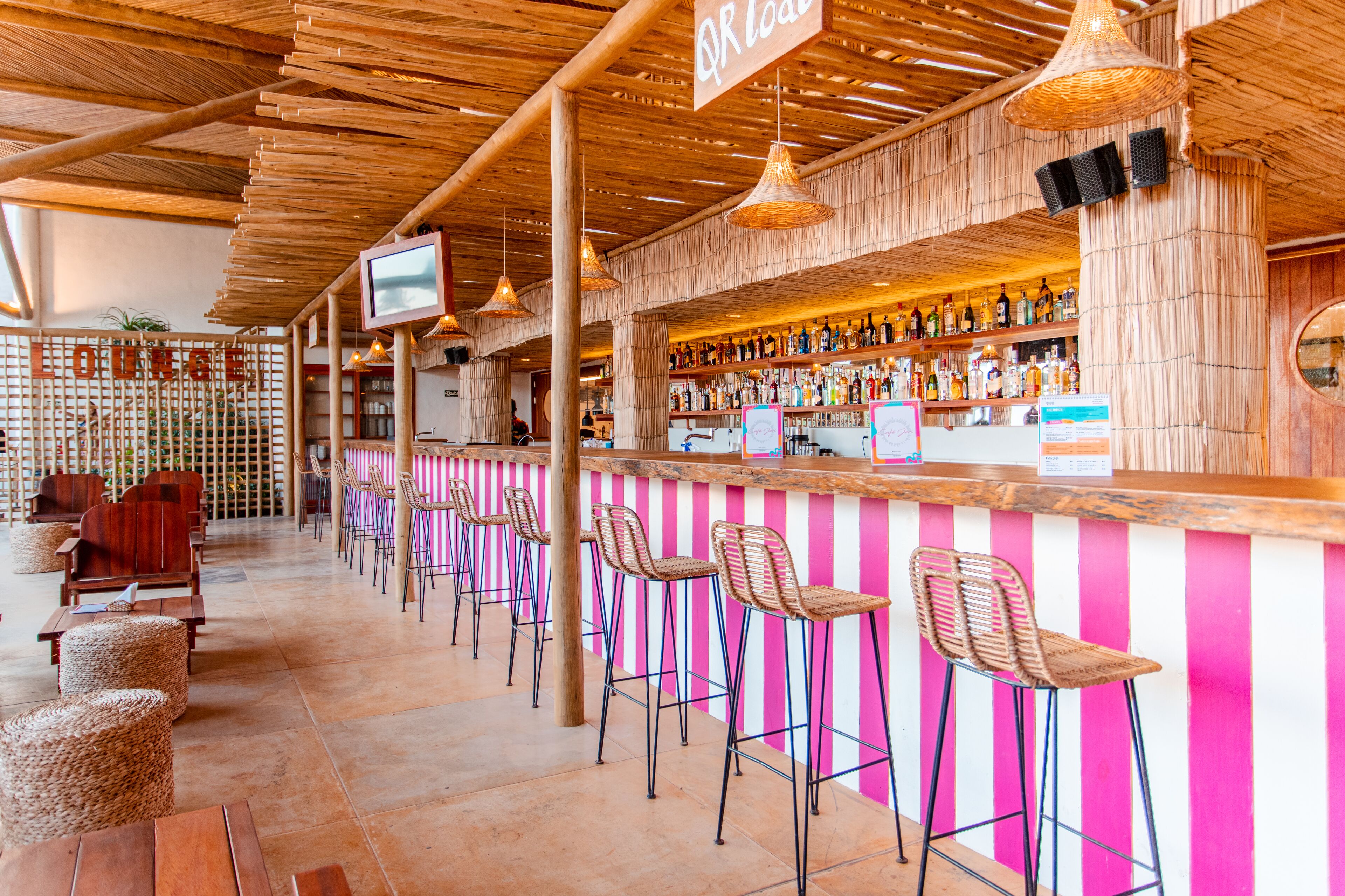 A bar area with wooden ceiling, striped wall, and bar stools.