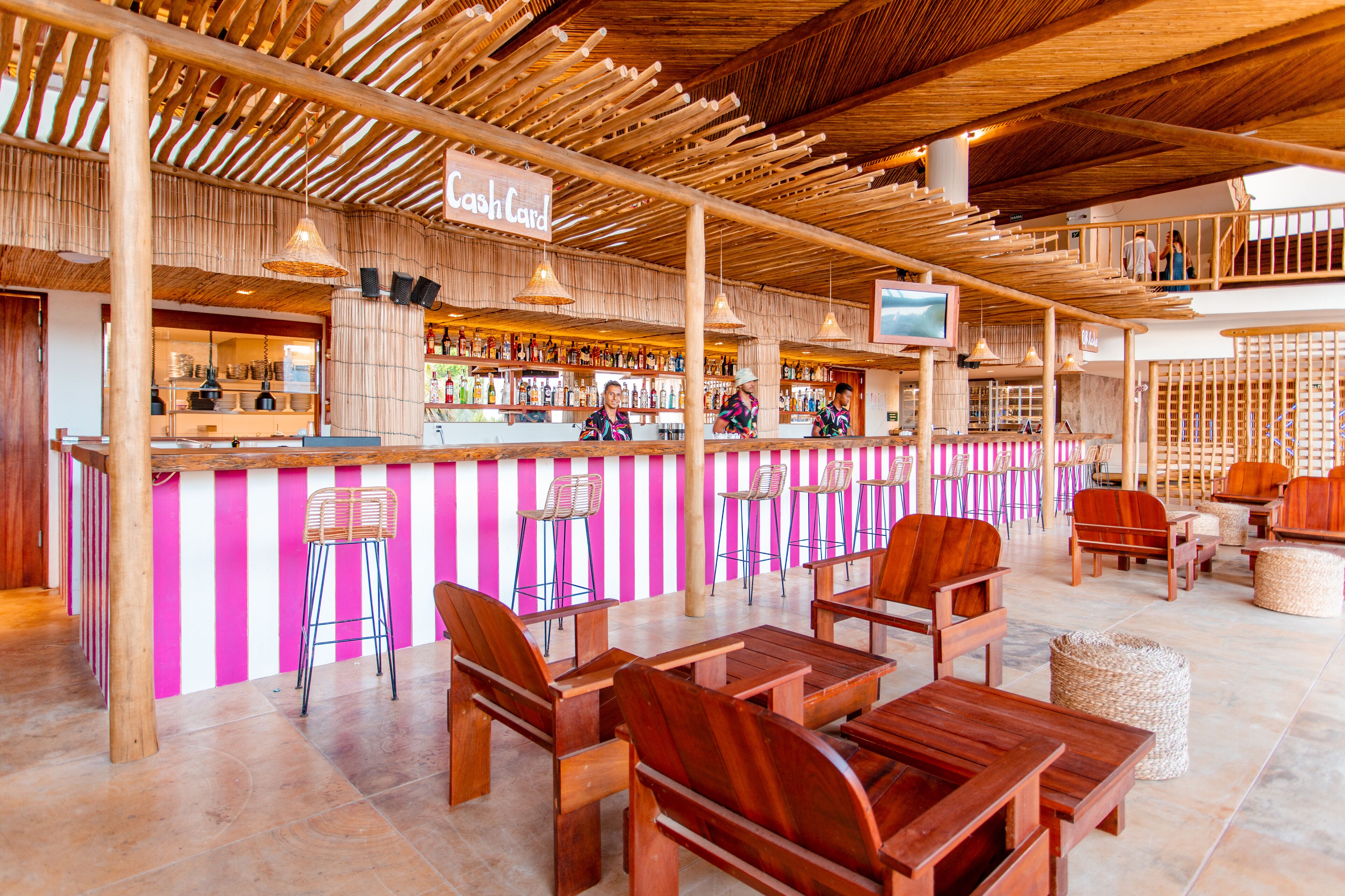 A bar area with wooden furniture and a pink and white striped wall.