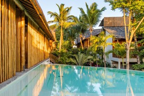 A pool area with bamboo walls and palm trees. - Café Jeri Hotel - Adults Only (Jijoca de Jericoacoara)
