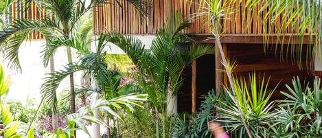 Un exuberante jardín con diversas plantas tropicales y una estructura de madera con balcón.