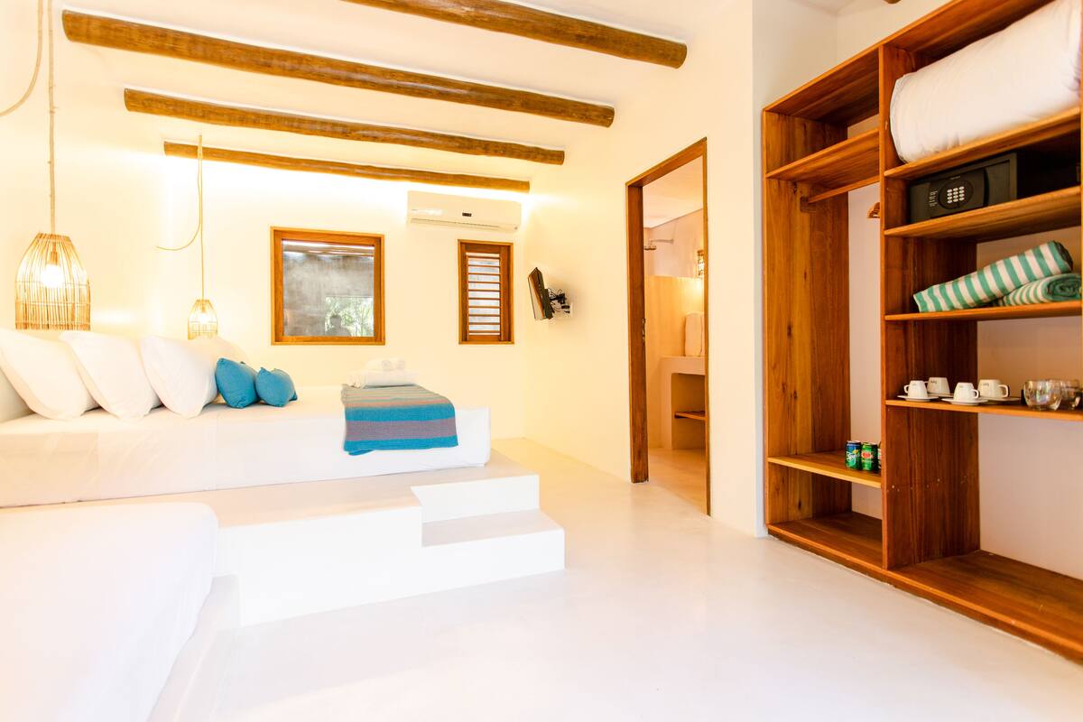 A modern hotel room with a white sofa, wooden shelves, and a staircase.