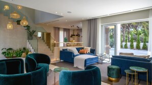 Un salon moderne avec un canapé bleu, une table basse et un escalier doté d’une rampe en verre.