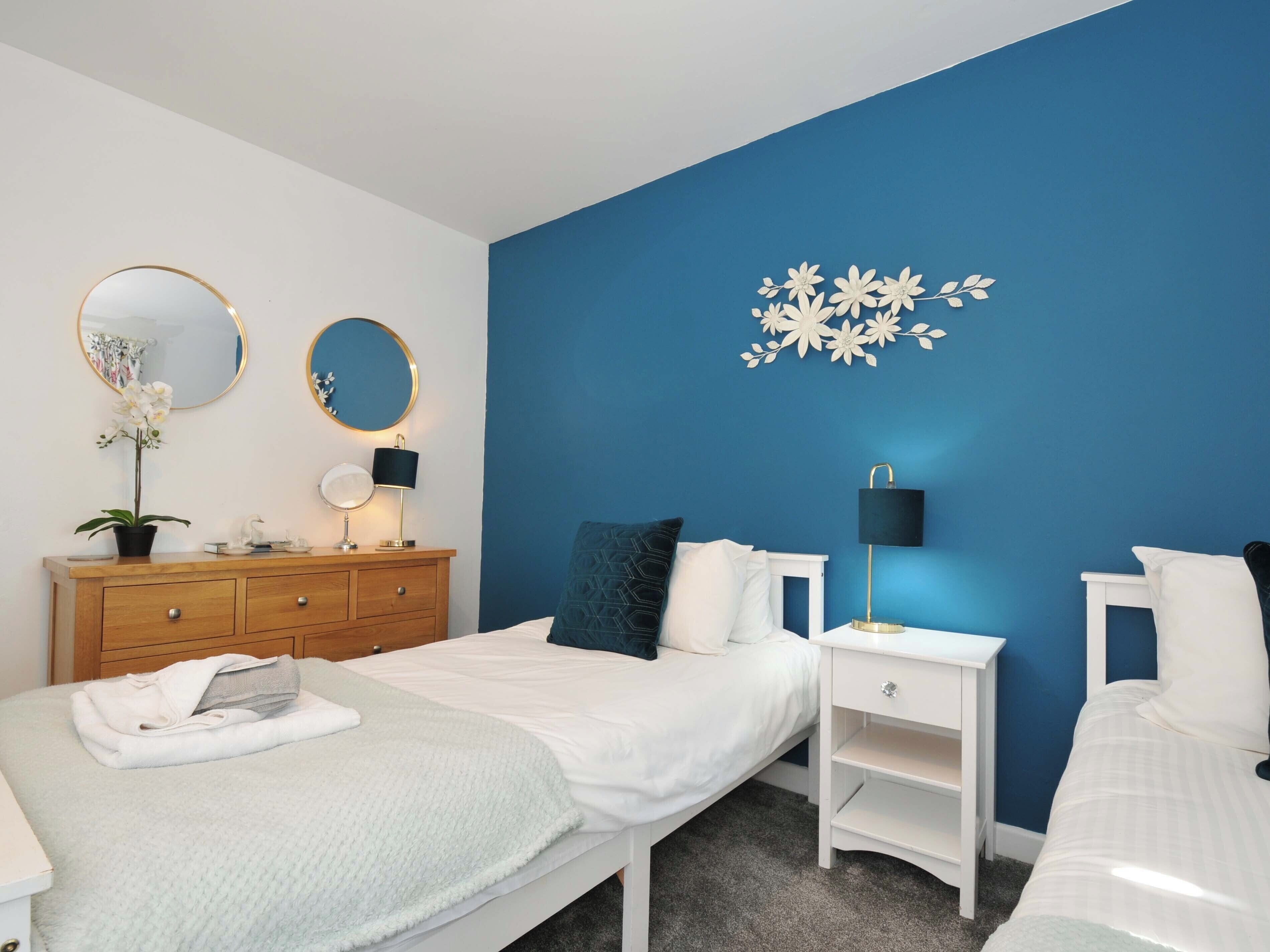 Une chambre avec deux lits, une commode et une table de chevet.