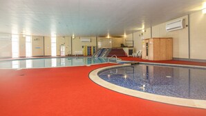 An indoor swimming pool with a red floor, a staircase leading to a higher level, and a wooden cabinet. - 60 Valley Lodge (Gunnislake)