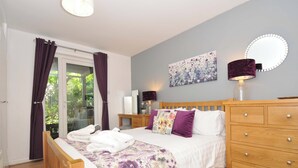 A bedroom with a bed, wooden dresser, and a mirror. - 60 Valley Lodge (Gunnislake)