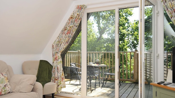 A room with a sliding glass door leading to an outdoor deck with a table and chairs. - 60 Valley Lodge (Gunnislake)