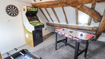 A room with a foosball table, a dartboard, and a 3D golf arcade game.