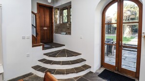 Una scala con gradini in pietra che conduce a una porta in legno, una piccola finestra e un campanello.