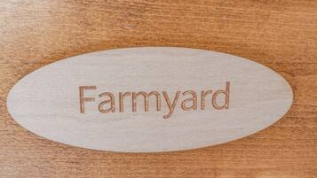 An oval wooden plaque with the word "Farmyard" engraved on it.