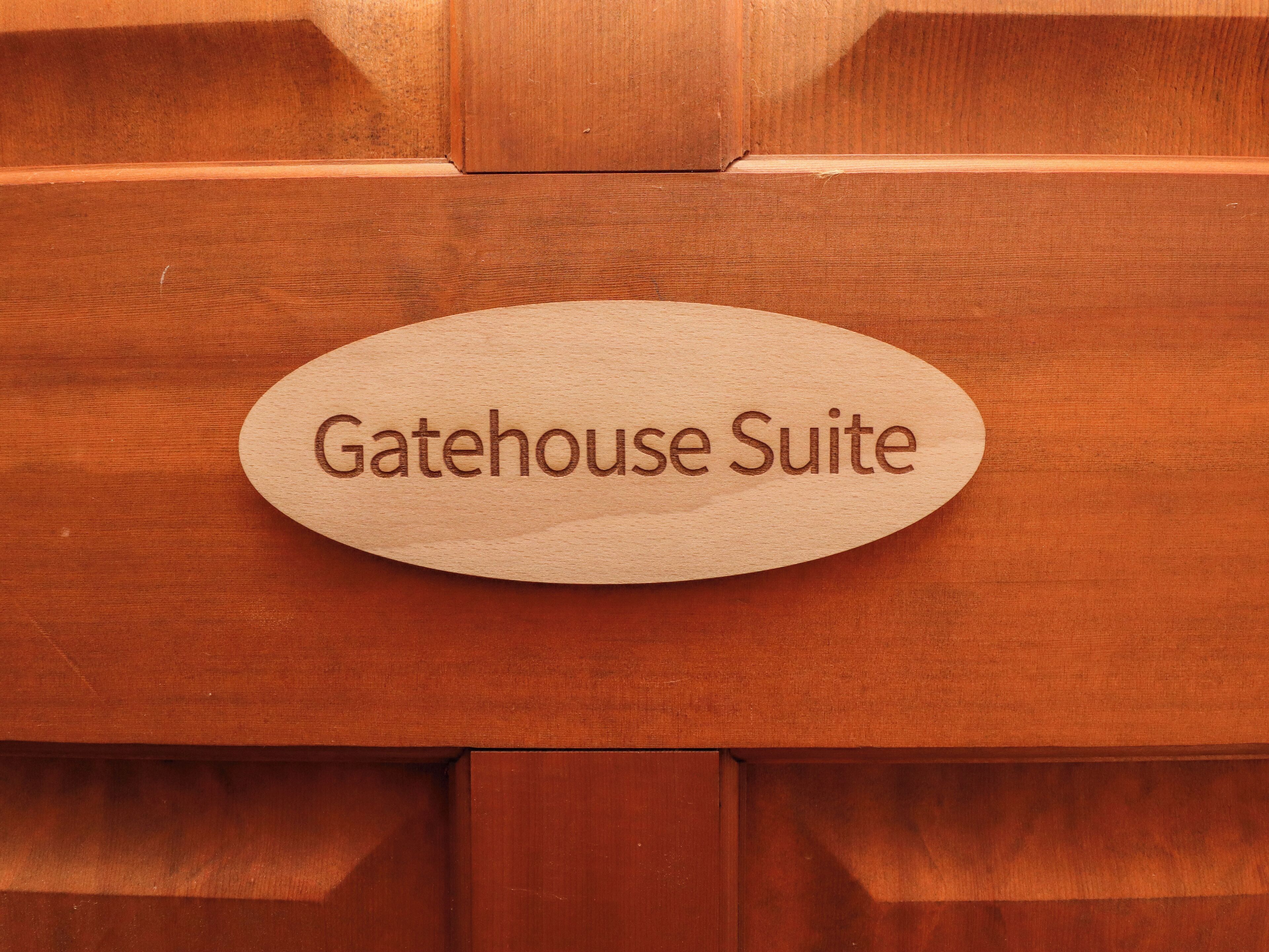 Un letrero de madera con el texto "Gatehouse Suite" sobre una superficie con textura.