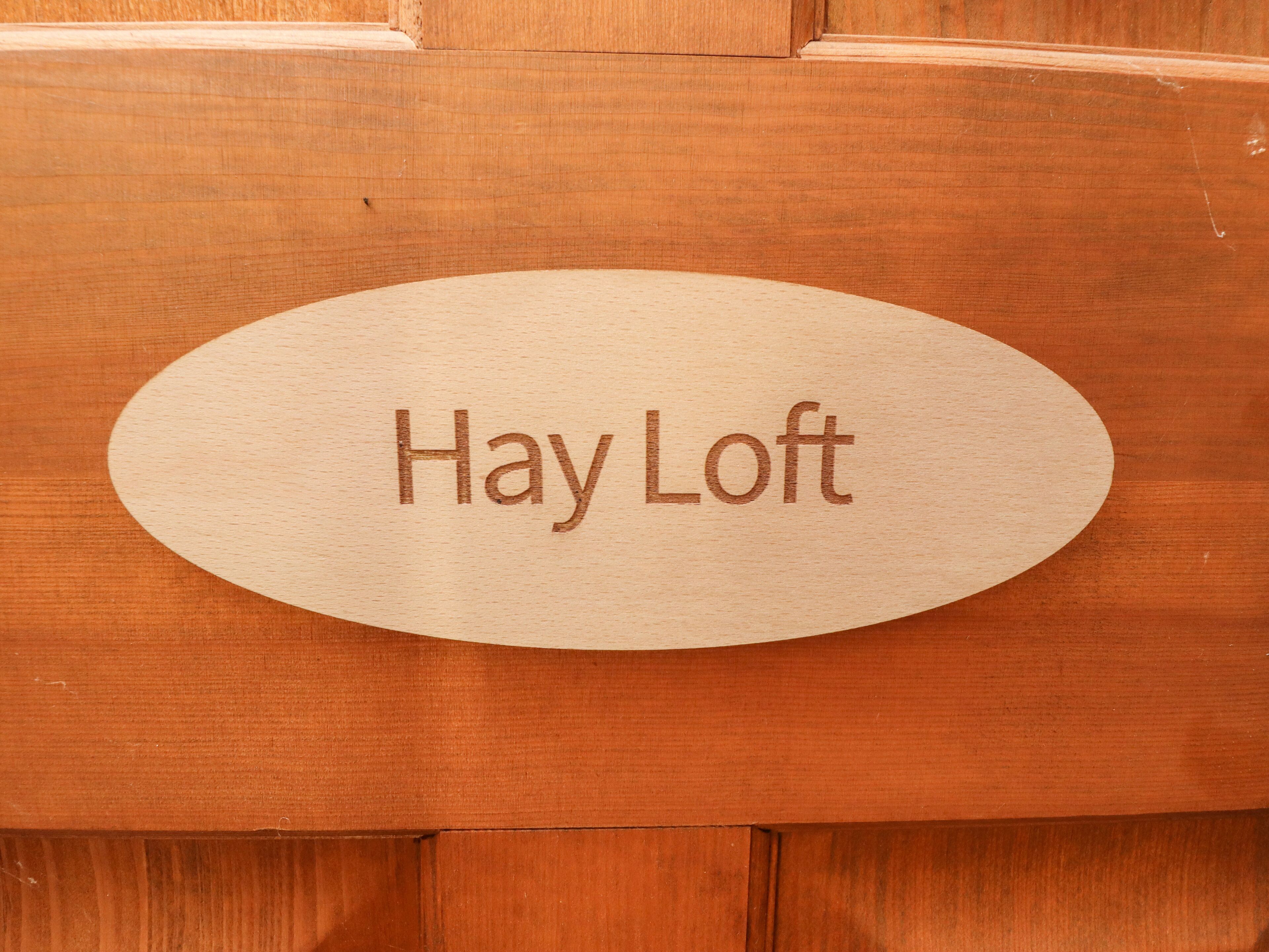 Egy fából készült tábla, amelyre a „Hay Loft” felirat van gravírozva.