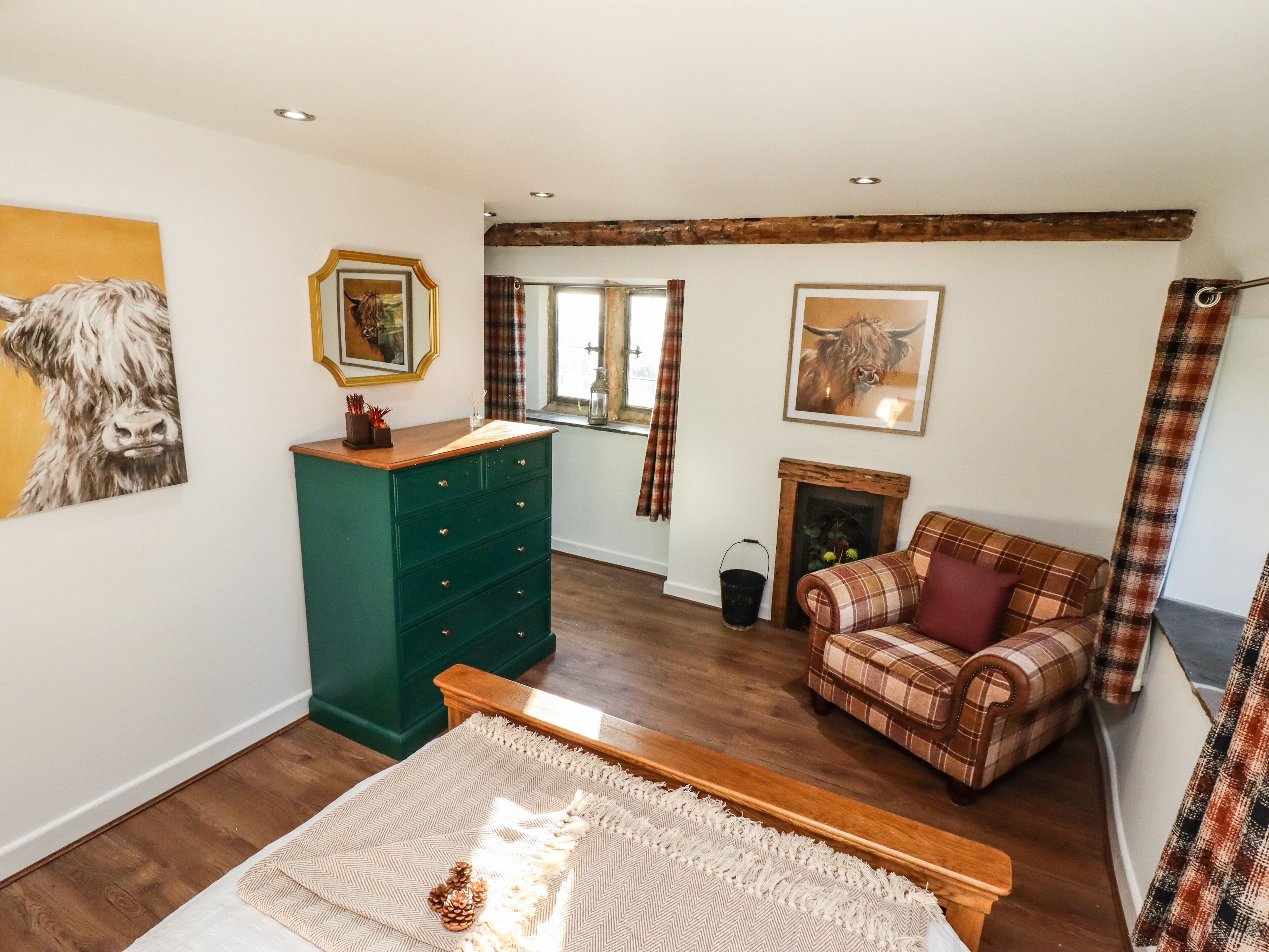 A cozy room with a green dresser, a plaid sofa, and a fireplace.
