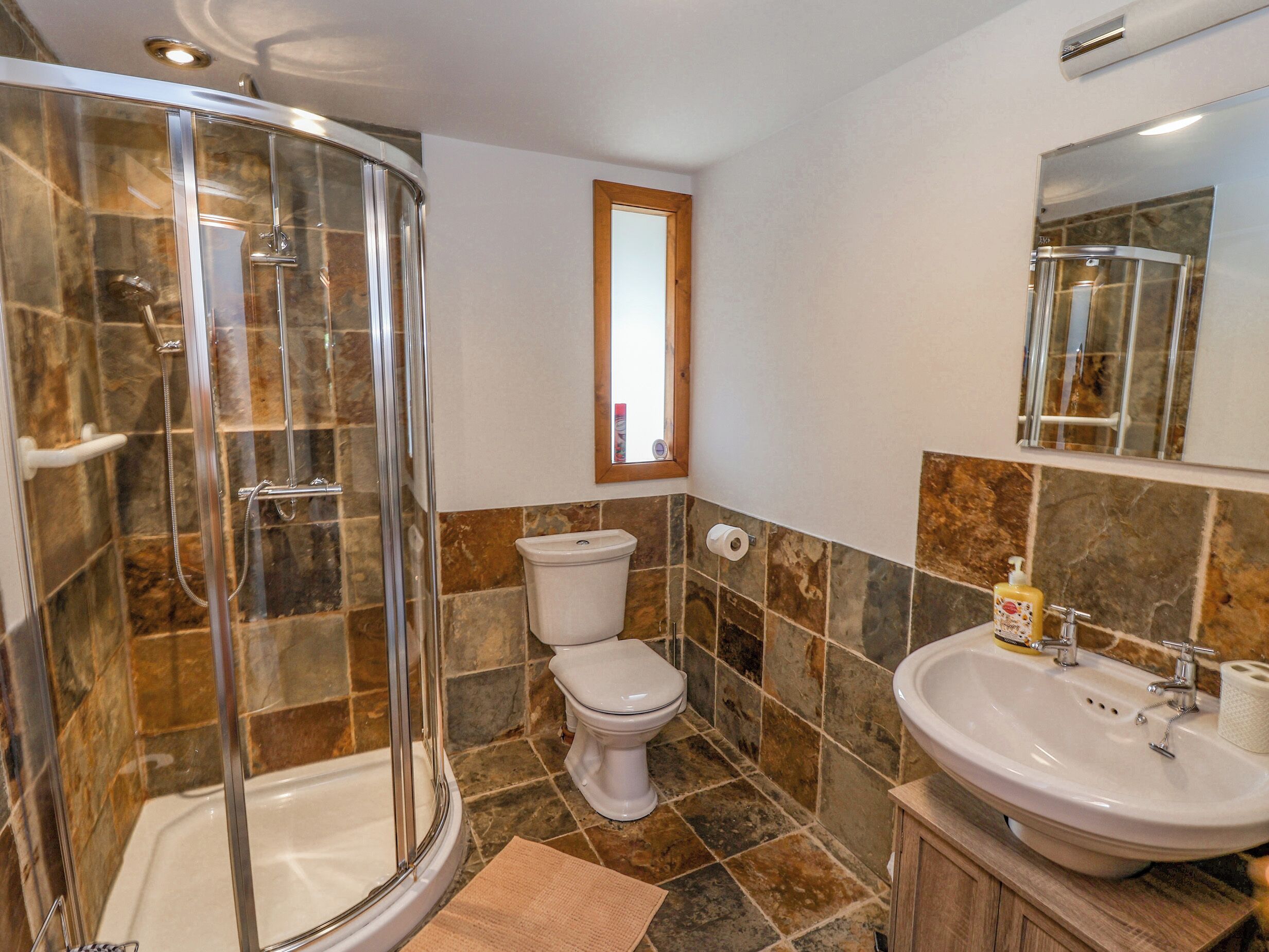 Un bagno con doccia vetrata, un water e un lavandino.
