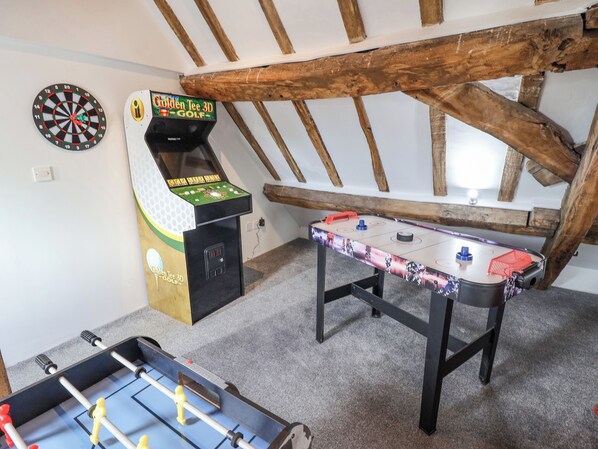 A room with a foosball table, a dartboard, and a 3D golf arcade game.