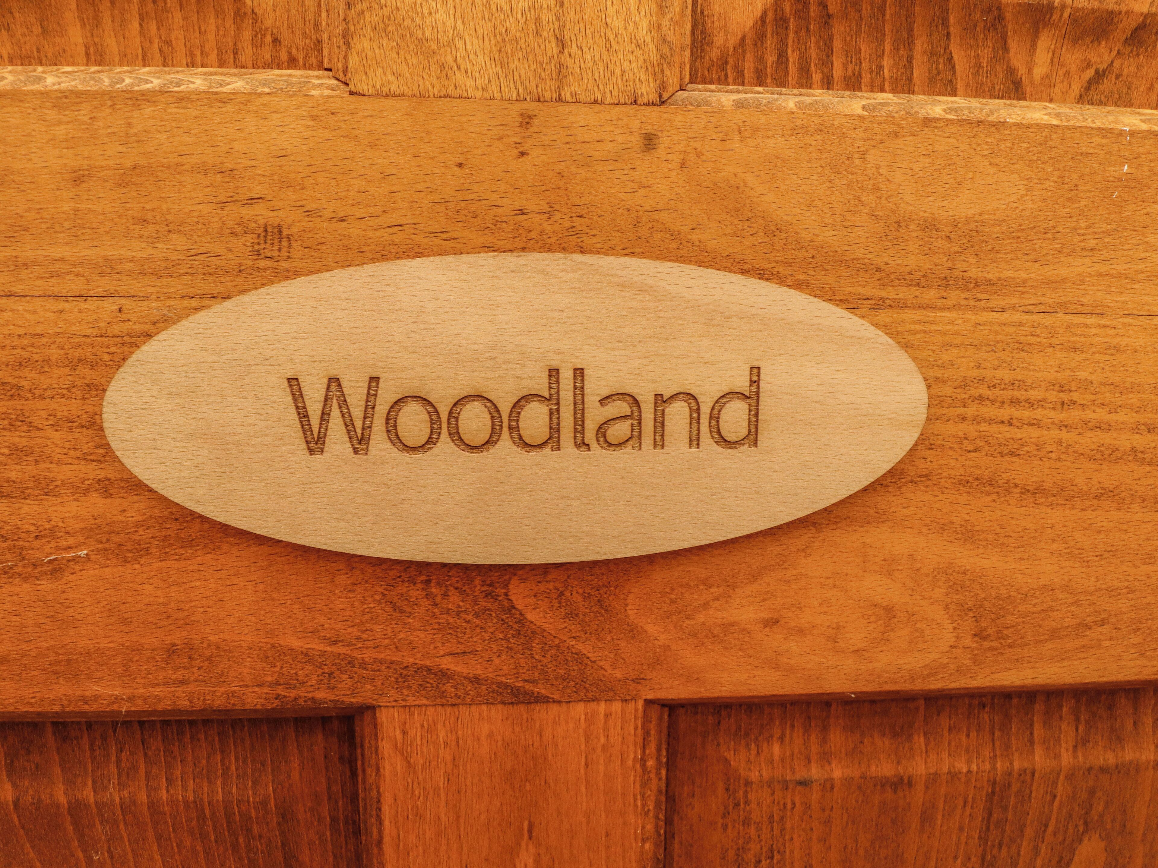 A wooden sign with the word "Woodland" engraved on it.