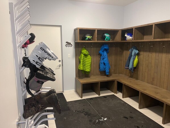 A locker room with benches and lockers, some with helmets and jackets hanging. - Lazy Moose Lodge - Luxurious, stylish mountain home with hot tub (Golden)