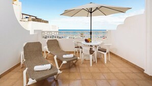Een balkon met twee loungestoelen, een tafel en een parasol.
