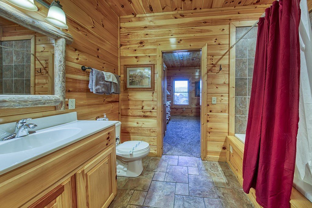 Ein Badezimmer in einer Holzhütte mit einem großen Waschbecken, einer Toilette und einem Duschbereich.