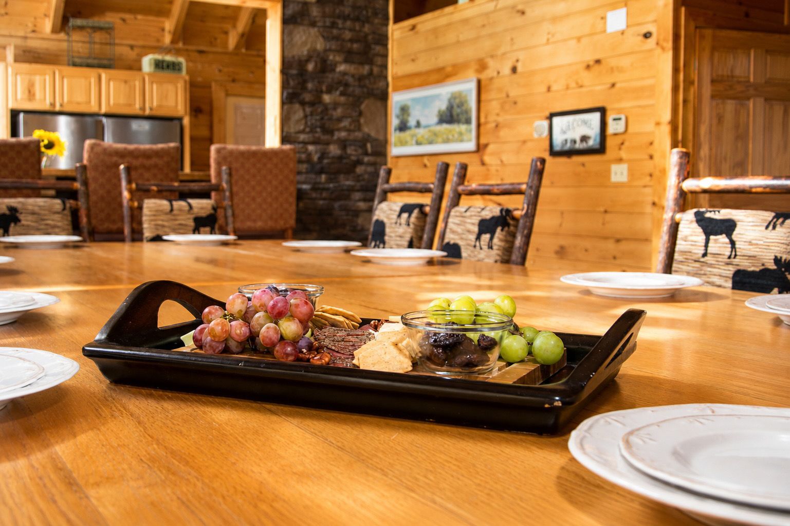 A wooden dining table with a charcuterie board in the center, surrounded by chairs with animal-themed cushions.