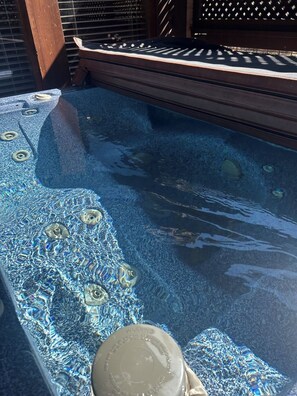 A hot tub with a textured blue surface and a wooden deck surrounding it. - Views! Sleeps 16! 4bed 4bath. 5 Min to Pigeon Forge! (Sevierville)