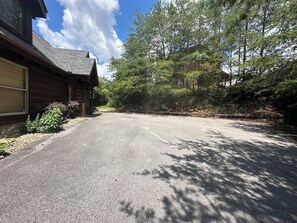 A paved driveway leading to a wooden cabin with a garage. - Views! Sleeps 16! 4bed 4bath. 5 Min to Pigeon Forge! (Sevierville)